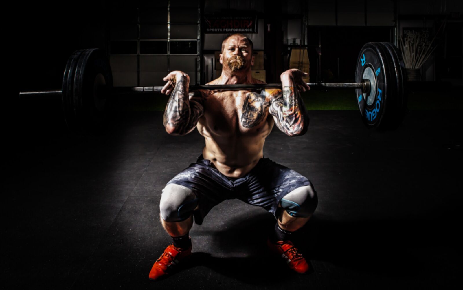 Client completing a heavy barbell squat during a coached strength session